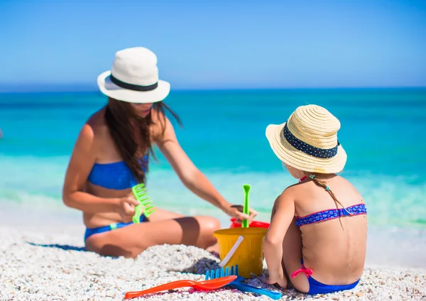 Söta lilla flicka och ung mamma bygga sandslott på tropical beach — Stockfoto