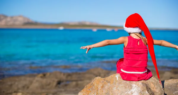 Adorable little girl in christmas hat during beach vacation — Stock Photo, Image
