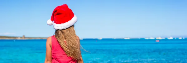 可爱的小女孩，在圣诞老人的帽子，在度假海滩上 — 图库照片