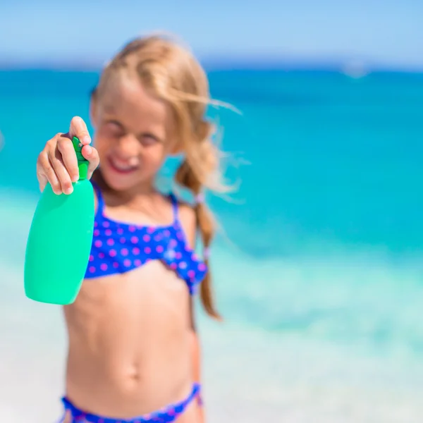 Schattig meisje in zwembroek met zonnebrand lotion fles — Stockfoto