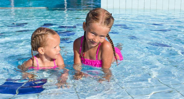 Bedårande glada små flickor att ha roligt i poolen Stockbild