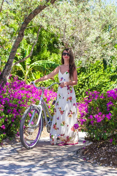 Giovane bella donna in vacanza in bicicletta in giardino lussureggiante — Foto Stock