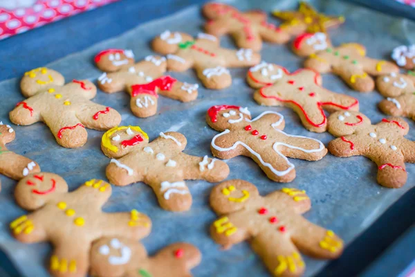 Raw gingerbread men with glaze on a baking sheet — Stock Photo, Image