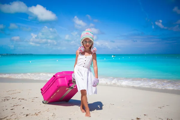 Bedårande flicka i varm vinter mössa och vantar gå med bagage på stranden — Stockfoto