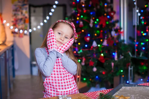 Adorable little girl in mittens baking Christmas gingerbread cookies — Stock Photo, Image
