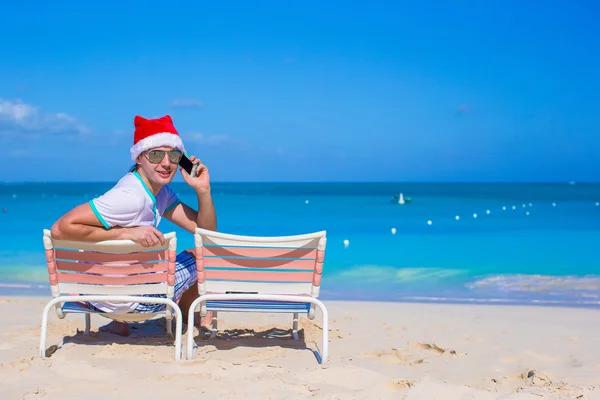 Young man in Christmas hat at beach chair — Stock Photo, Image