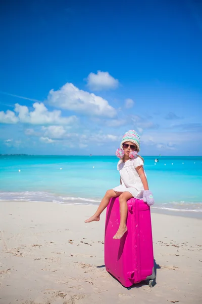Entzückendes Mädchen mit warmem Winterhut und Fäustlingen, die mit Gepäck am Strand spazieren gehen — Stockfoto