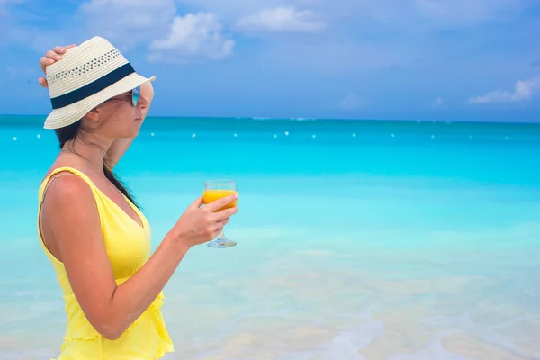 Апельсиновый сок в женской руке на фоне моря — стоковое фото