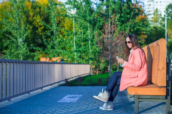 若い女性は、秋の日に彼女の携帯電話で写真を撮る — ストック写真