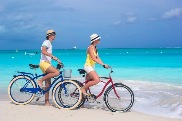 Giovane coppia felice in sella a biciclette sulla spiaggia tropicale bianca — Foto Stock