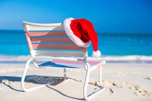 Closeup červený Santa klobouk na křeslo longue na tropické pláži — Stock fotografie
