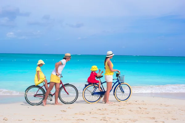 En ung, lykkelig familie som sykler på strandferie – stockfoto
