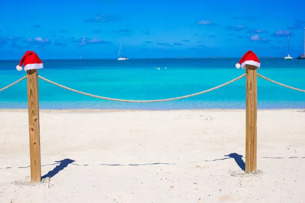 Zwei rote Weihnachtsmänner am Zaun am tropischen weißen Strand — Stockfoto