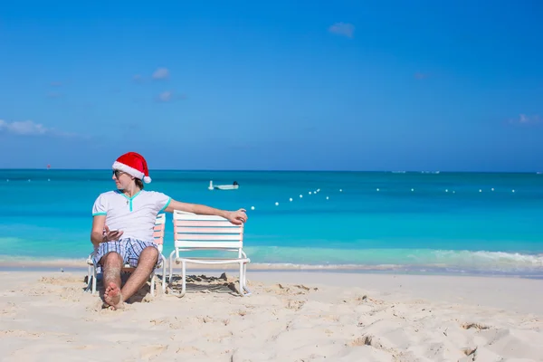 Mladý muž v santa hat během pláž dovolená — Stock fotografie