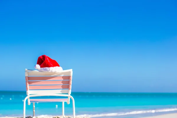 Primer plano rojo Santa sombrero en silla longue en la playa tropical —  Fotos de Stock