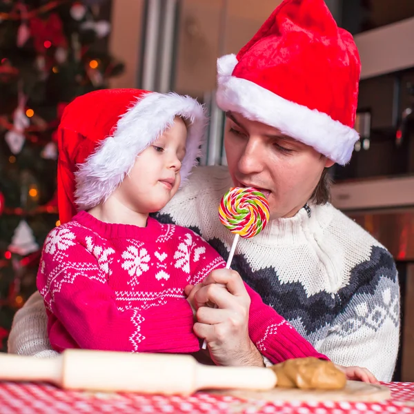 Papá joven y su hija pequeña en Santa sombrero hornear galletas de jengibre de Navidad — Foto de Stock