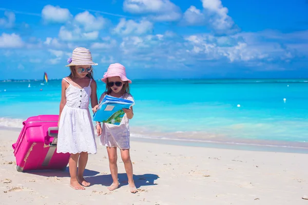 Küçük kızlarla büyük bavul ve tropikal plaj yolda arama harita — Stok fotoğraf