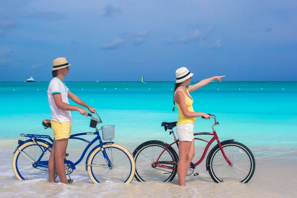 年轻幸福的夫妇，在白色的热带海滩上骑自行车 — 图库照片