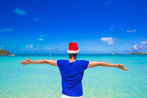 Jeune homme en chapeau de Père Noël rouge sur la plage tropicale — Photo