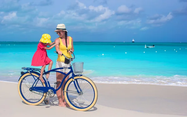 Happy mother and daughter riding bicycles on tropical beach — Stock Photo, Image