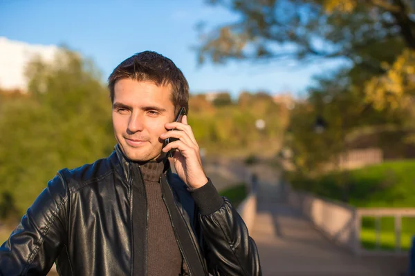 Jeune homme avec un téléphone dans le parc — Photo