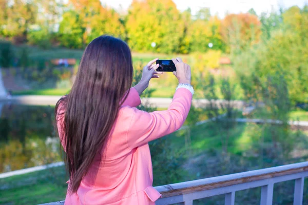 Genç kadın sonbahar günü onu telefonla bir fotoğraf almak — Stok fotoğraf