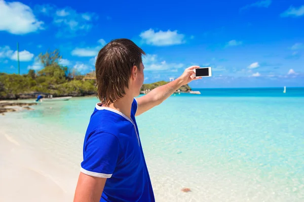 Młody mężczyzna z telefonu na tropikalnej plaży Karaiby — Zdjęcie stockowe
