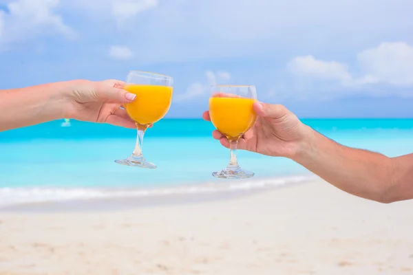 Två händer hålla glasögon med apelsinjuice bakgrunden blå himmel — Stockfoto