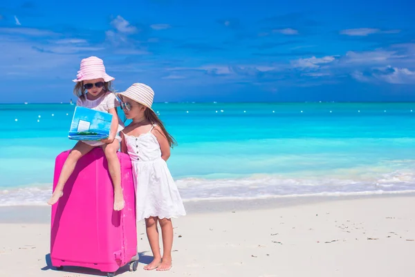 Little girls with big suitcase and map on tropical beach — Stock Photo, Image