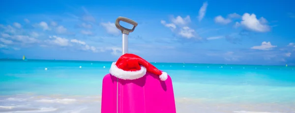 Крупним планом рожеві валізу і Санта-Клауса капелюх на пляжі — стокове фото