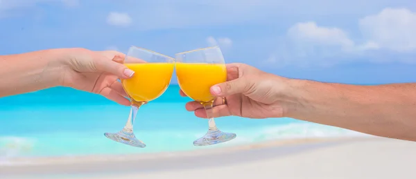 Duas mãos segurar óculos com fundo de suco de laranja céu azul — Fotografia de Stock