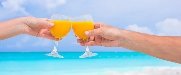 Две руки держат стаканы на фоне голубого неба и бирюзового моря — стоковое фото
