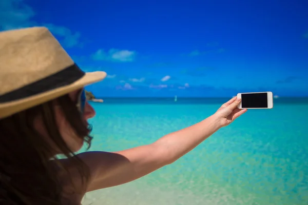 Mujer joven tomar una foto en su teléfono en la playa tropical —  Fotos de Stock