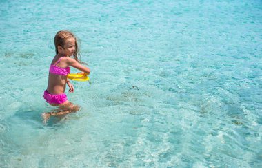 Küçük kız denizde sırasında tatil tropikal frizbi oynamaya