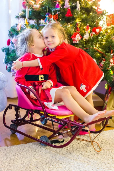 Kleine meisjes verkleed als Santa in de buurt van de kerstboom — Stockfoto