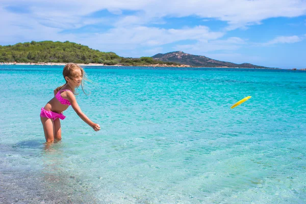 Liten flicka spela frisbee under tropiska semester i havet — Stockfoto