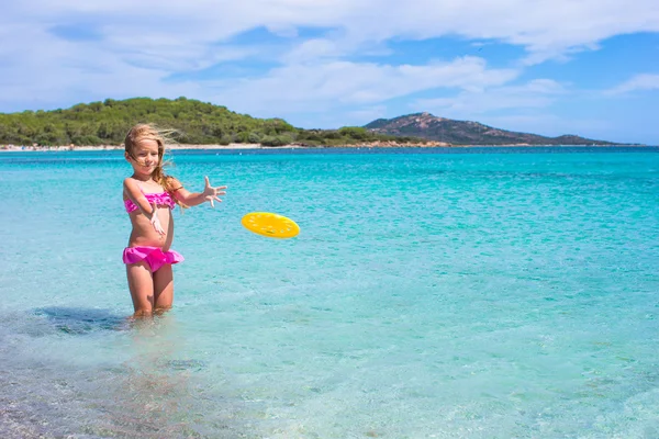 Küçük kız denizde sırasında tatil tropikal frizbi oynamaya — Stok fotoğraf