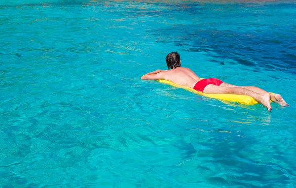 Young man relaxing on inflatable mattress in the sea — Stock Photo, Image