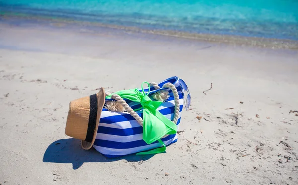 Stripe bag, straw hat, sunblock and towel on white tropical beach — Stock Photo, Image