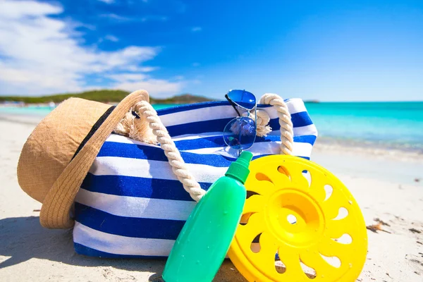 Полосатый мешок, соломенная шляпа, солнцезащитный крем и полотенце на белом тропическом пляже — стоковое фото