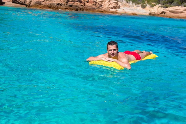 Hombre feliz que relaja en colchón inflable en mar claro — Foto de Stock