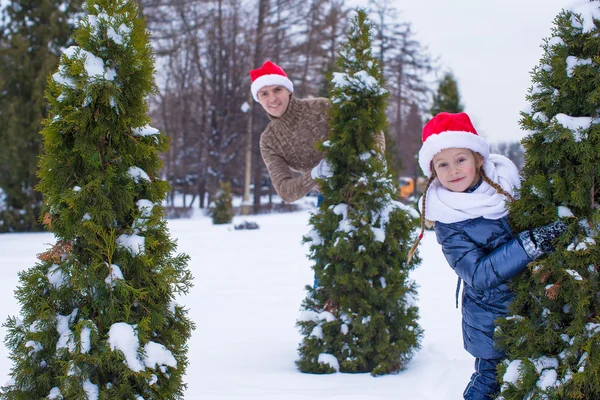 Joyeux père et enfant dans chapeaux de Noël avec arbre de Noël en plein air — Photo