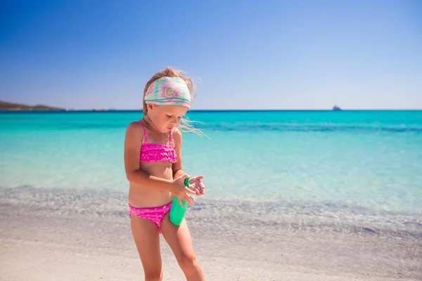 Petite fille adorable en maillot de bain avec bouteille de lotion solaire — Photo