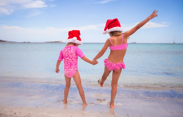 Little adorable girls in Santa hats during beach vacation — Stock Photo, Image
