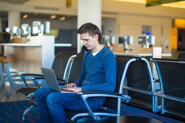 Jovem com um laptop no aeroporto enquanto espera seu voo — Fotografia de Stock