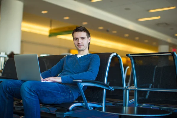 Young man with a laptop at the airport while waiting his flight — Stock Photo, Image