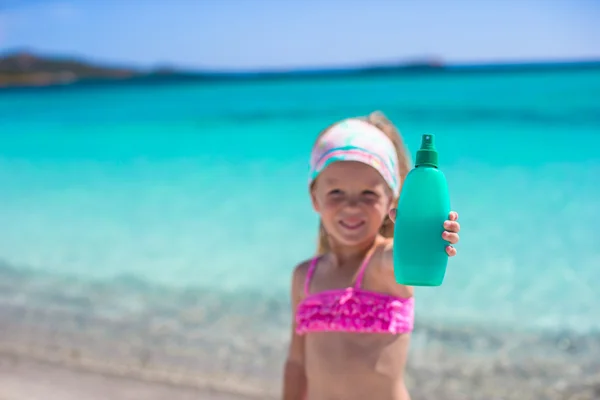 Piccola adorabile ragazza in costume da bagno con bottiglia di crema abbronzante — Foto Stock