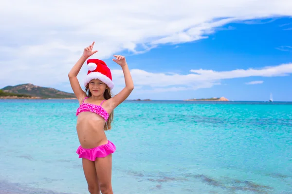 Piccola adorabile ragazza in rosso cappello di Babbo Natale sulla spiaggia tropicale — Foto Stock