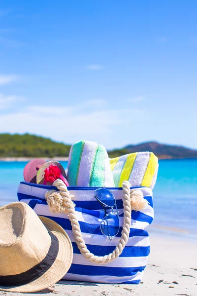 Blaue Tasche, Strohhut, Flip Flops und Handtuch am weißen Strand — Stockfoto