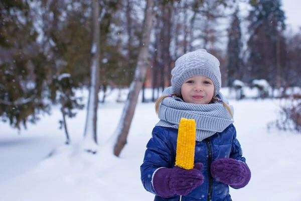 Piccola adorabile ragazza che mangia mais nel parco invernale — Foto Stock